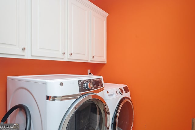 clothes washing area featuring cabinets and washing machine and dryer