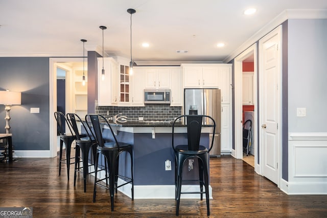 kitchen with a kitchen bar, kitchen peninsula, pendant lighting, stainless steel appliances, and white cabinets