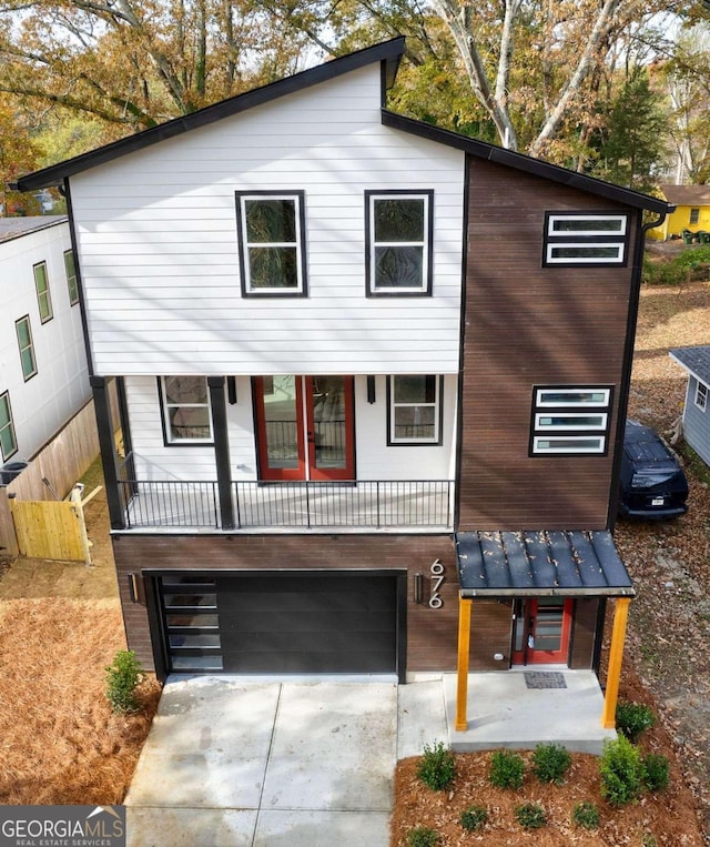 contemporary home with a standing seam roof, covered porch, driveway, and metal roof