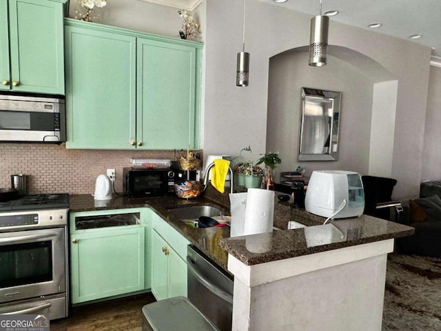 kitchen with sink, stainless steel appliances, tasteful backsplash, decorative light fixtures, and dark stone counters