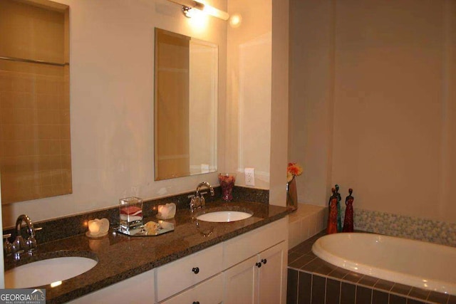 bathroom with tiled tub and vanity