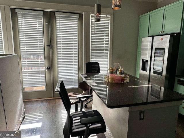 kitchen with a breakfast bar, green cabinetry, stainless steel refrigerator, dark hardwood / wood-style floors, and pendant lighting