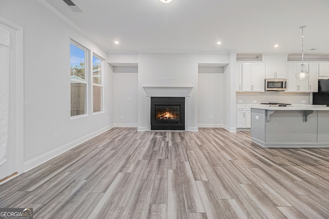 kitchen featuring a breakfast bar area, white cabinetry, tasteful backsplash, hanging light fixtures, and light wood-type flooring