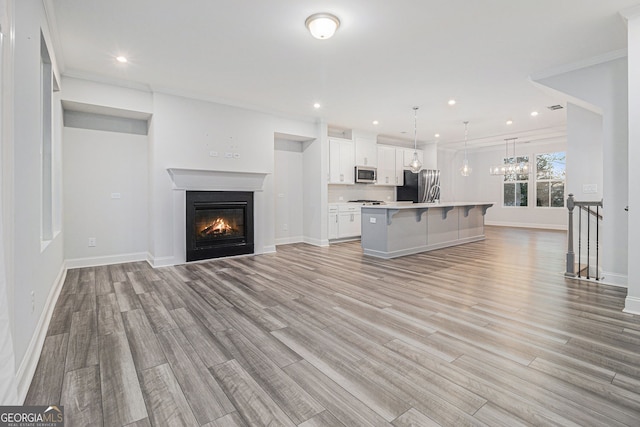 unfurnished living room featuring ornamental molding and light hardwood / wood-style floors