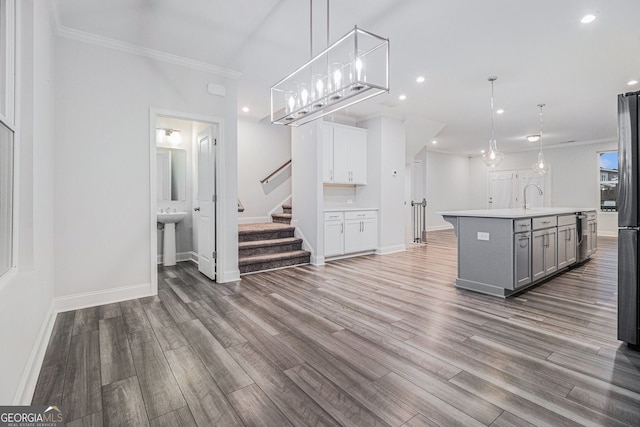 interior space featuring pendant lighting, hardwood / wood-style floors, gray cabinetry, and a center island with sink