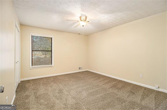 empty room with ceiling fan, a textured ceiling, and carpet flooring