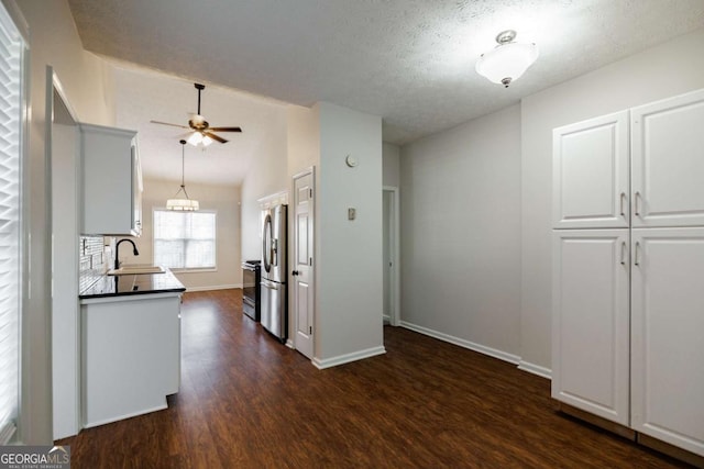 kitchen with vaulted ceiling, sink, white cabinets, stainless steel fridge, and dark hardwood / wood-style flooring