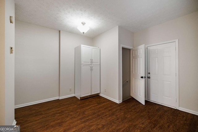 unfurnished bedroom with dark wood-type flooring and a textured ceiling