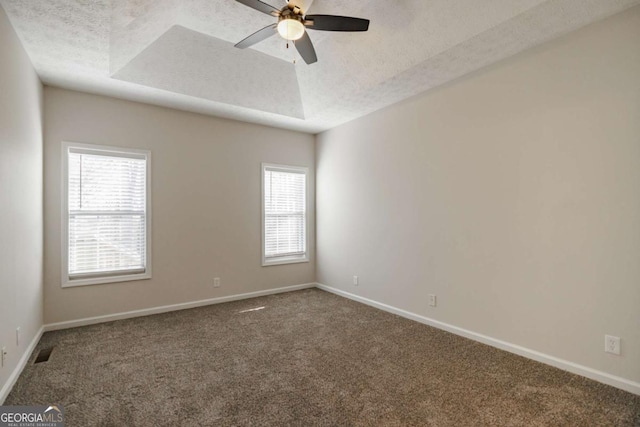 carpeted spare room with ceiling fan, a tray ceiling, and a textured ceiling