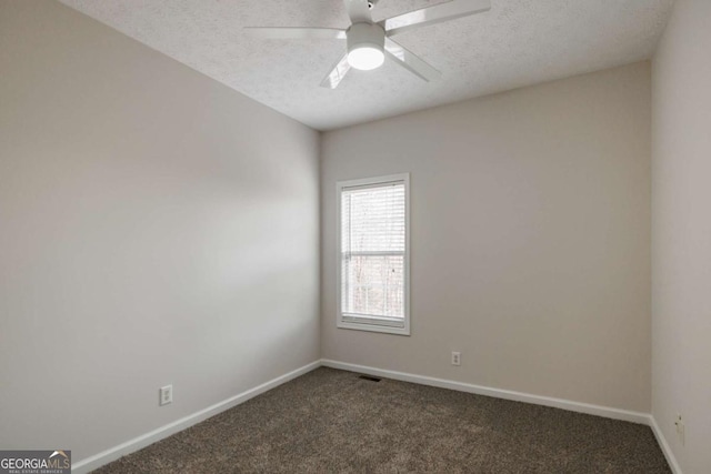 empty room with ceiling fan, dark carpet, and a textured ceiling