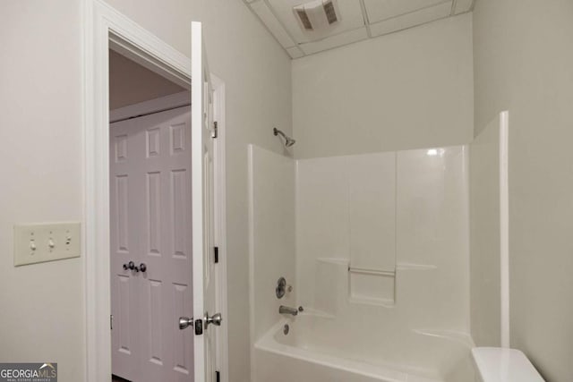 bathroom with a drop ceiling and  shower combination