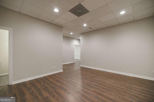 spare room featuring dark hardwood / wood-style flooring and a drop ceiling