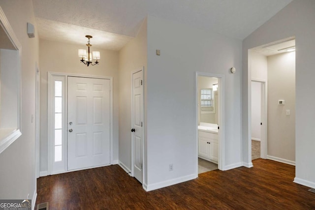 entrance foyer with dark hardwood / wood-style flooring, lofted ceiling, and a chandelier