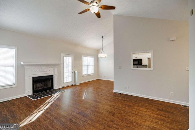 unfurnished living room featuring ceiling fan, a fireplace, dark hardwood / wood-style flooring, and vaulted ceiling