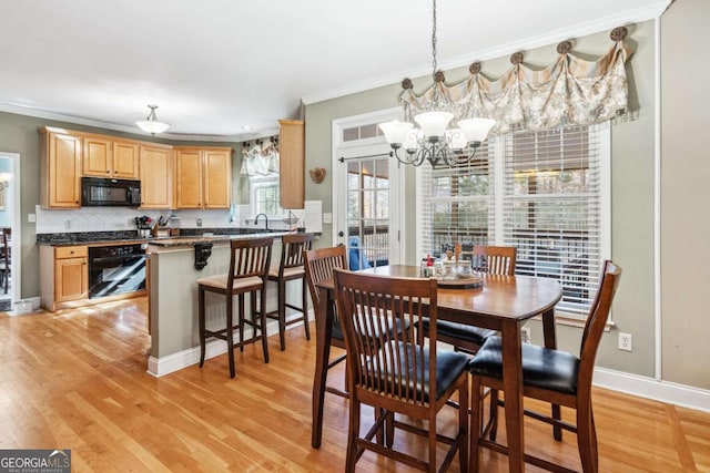 dining space featuring ornamental molding, a notable chandelier, and light hardwood / wood-style flooring