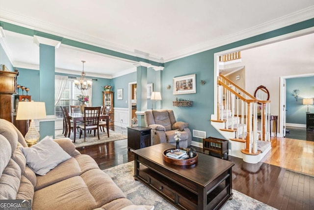 living room with an inviting chandelier, hardwood / wood-style floors, and crown molding