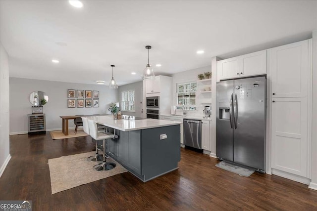 kitchen featuring a kitchen island, white cabinetry, appliances with stainless steel finishes, and pendant lighting