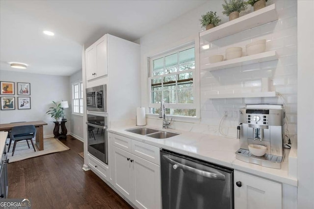 kitchen with sink, stainless steel appliances, light stone countertops, white cabinets, and dark hardwood / wood-style flooring