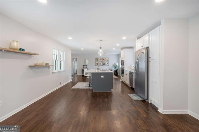 kitchen featuring white cabinetry, a kitchen breakfast bar, a center island, stainless steel appliances, and decorative light fixtures