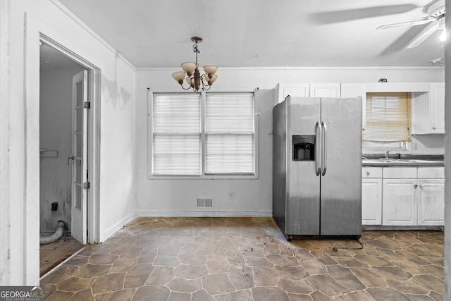 kitchen with hanging light fixtures, stainless steel fridge, ornamental molding, and white cabinets