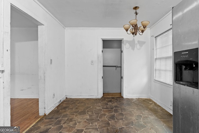 unfurnished dining area featuring crown molding and a chandelier