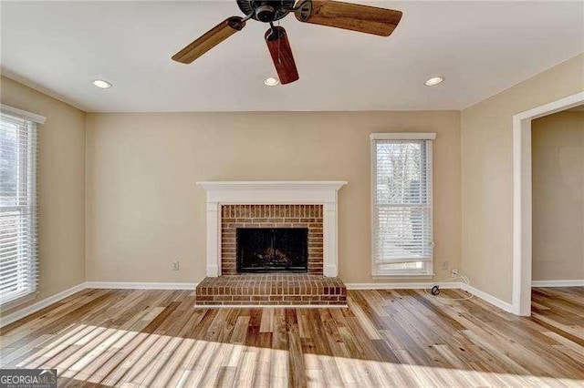 unfurnished living room featuring ceiling fan, a fireplace, and light hardwood / wood-style floors