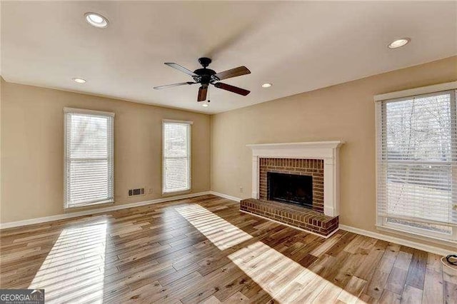 unfurnished living room featuring wood-type flooring, ceiling fan, and a fireplace