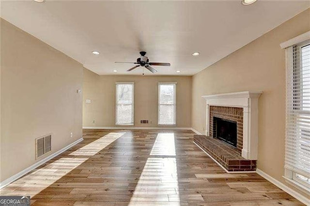 unfurnished living room featuring ceiling fan, a fireplace, and light wood-type flooring