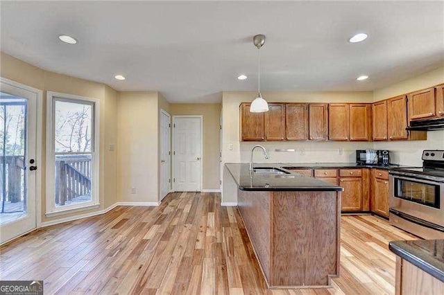 kitchen featuring stainless steel electric range oven, sink, hanging light fixtures, and light wood-type flooring