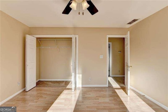 unfurnished bedroom with ceiling fan, light wood-type flooring, and a closet