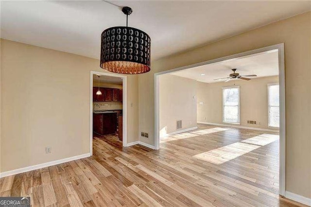 unfurnished dining area with ceiling fan, sink, and light wood-type flooring