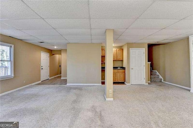 basement featuring a paneled ceiling and carpet flooring