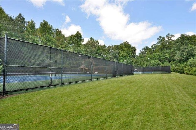 view of tennis court featuring a lawn