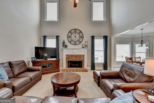 living room with a towering ceiling, a fireplace, a notable chandelier, crown molding, and light carpet