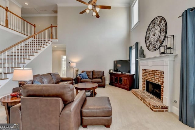 carpeted living room with a fireplace, ornamental molding, ceiling fan, and a high ceiling