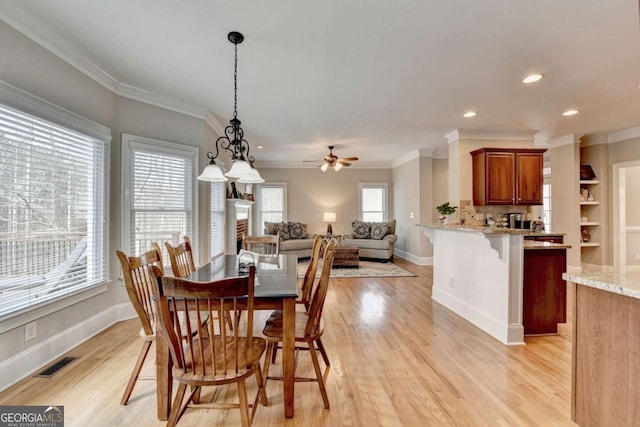 dining room with light hardwood / wood-style flooring, ornamental molding, and ceiling fan