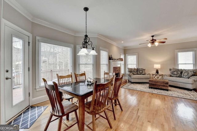 dining area with crown molding, a brick fireplace, and light hardwood / wood-style floors