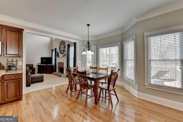 dining room with crown molding, an inviting chandelier, a fireplace, and light hardwood / wood-style floors