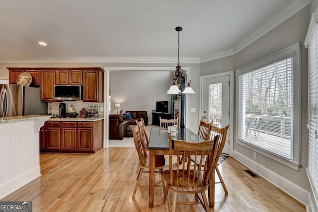 dining space with ornamental molding and light hardwood / wood-style floors