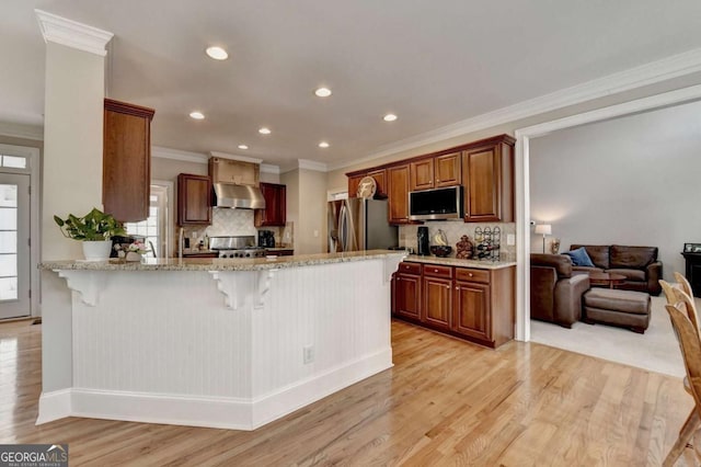 kitchen featuring light hardwood / wood-style flooring, a breakfast bar area, stainless steel appliances, and kitchen peninsula