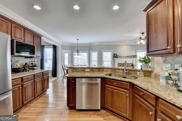 kitchen featuring sink, crown molding, decorative light fixtures, appliances with stainless steel finishes, and light stone countertops