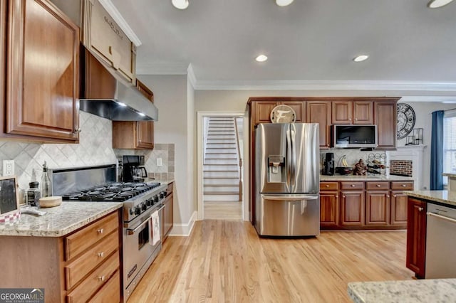 kitchen featuring stainless steel appliances, ornamental molding, light wood-type flooring, and decorative backsplash