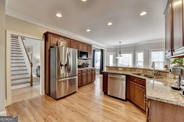 kitchen featuring appliances with stainless steel finishes, decorative light fixtures, sink, light stone counters, and a healthy amount of sunlight