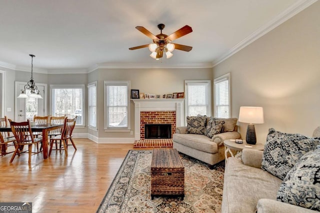 living room featuring crown molding, plenty of natural light, light hardwood / wood-style floors, and a brick fireplace