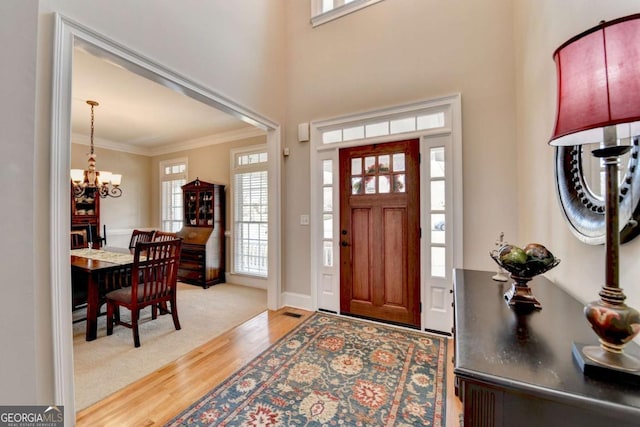 foyer featuring an inviting chandelier, hardwood / wood-style floors, and ornamental molding