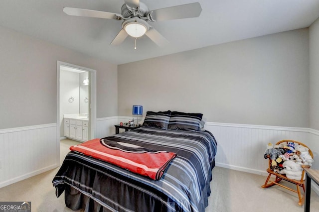 carpeted bedroom with ensuite bath and ceiling fan