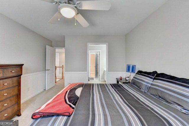 bedroom with ceiling fan, light colored carpet, and ensuite bath