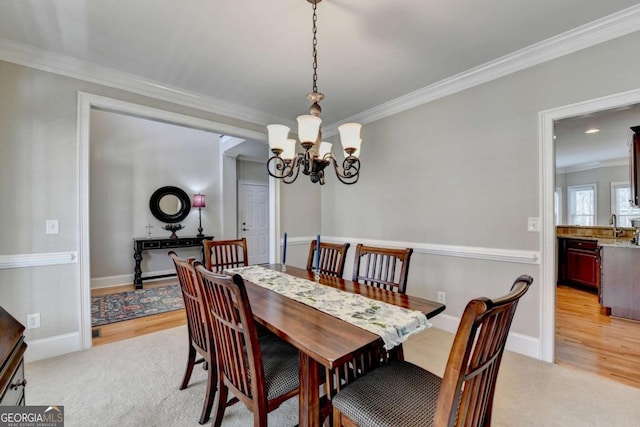 carpeted dining space with ornamental molding and a chandelier