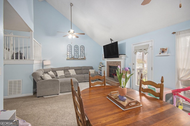 carpeted dining space featuring ceiling fan, a fireplace, and high vaulted ceiling