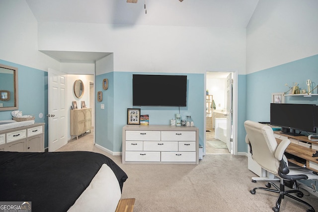 bedroom with a towering ceiling, connected bathroom, and light carpet